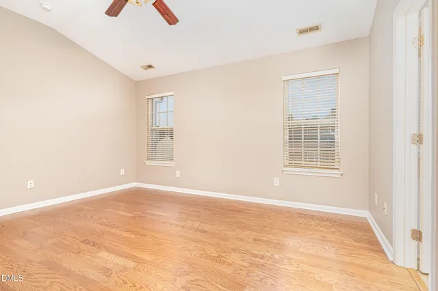 an empty room with wooden floor and ceiling fan