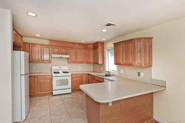 a kitchen with a sink a stove a refrigerator a kitchen island and chairs