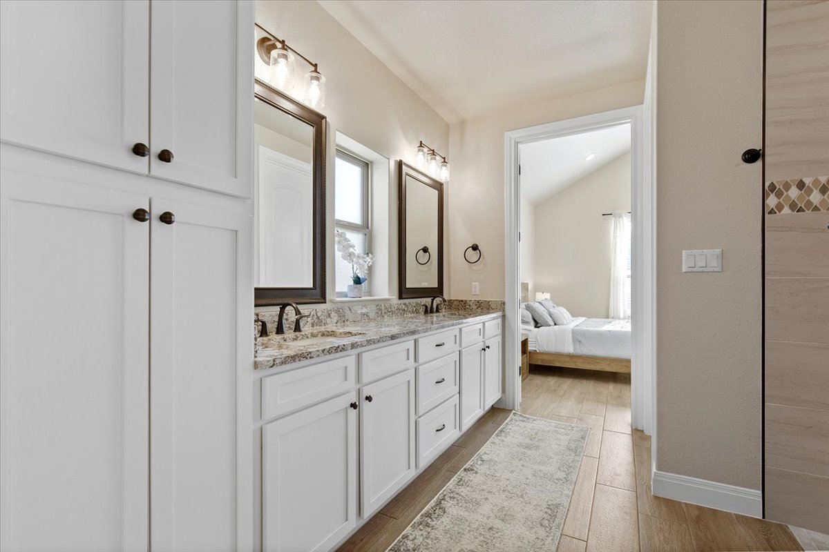 304 Morning Ridge Georgetown, TX 78628 - Photo 19 of 31 Full bathroom featuring double vanity, wood finish floors, vaulted ceiling, and ensuite bath