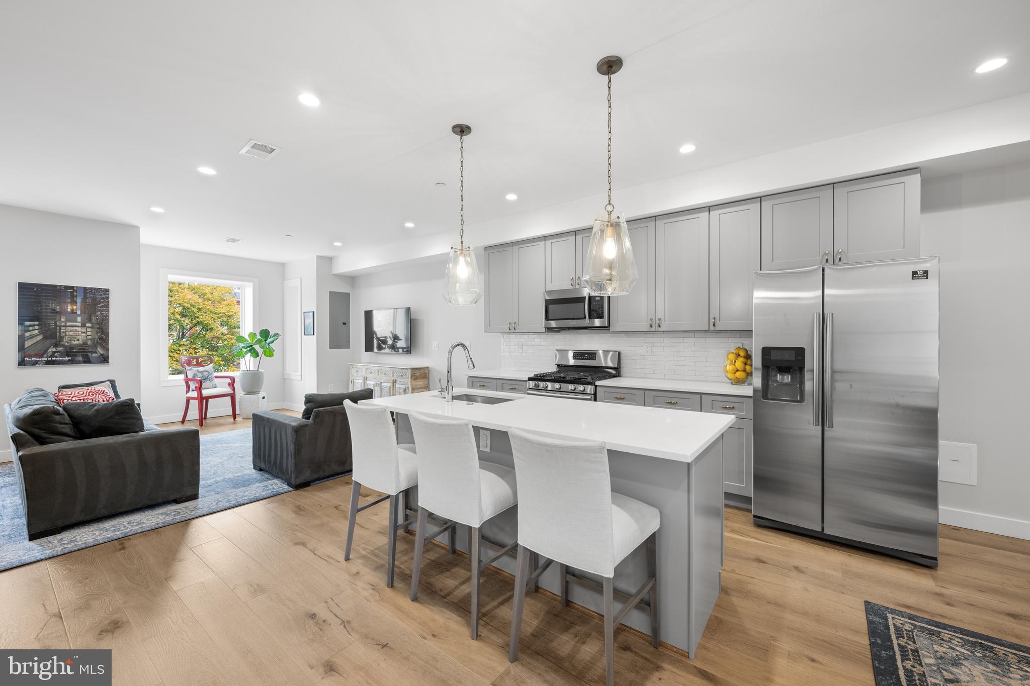127 R Street Northeast, Unit 2 Washington, DC 20002 - Photo 5 of 31 a kitchen with kitchen island a dining table chairs wooden floor and appliances