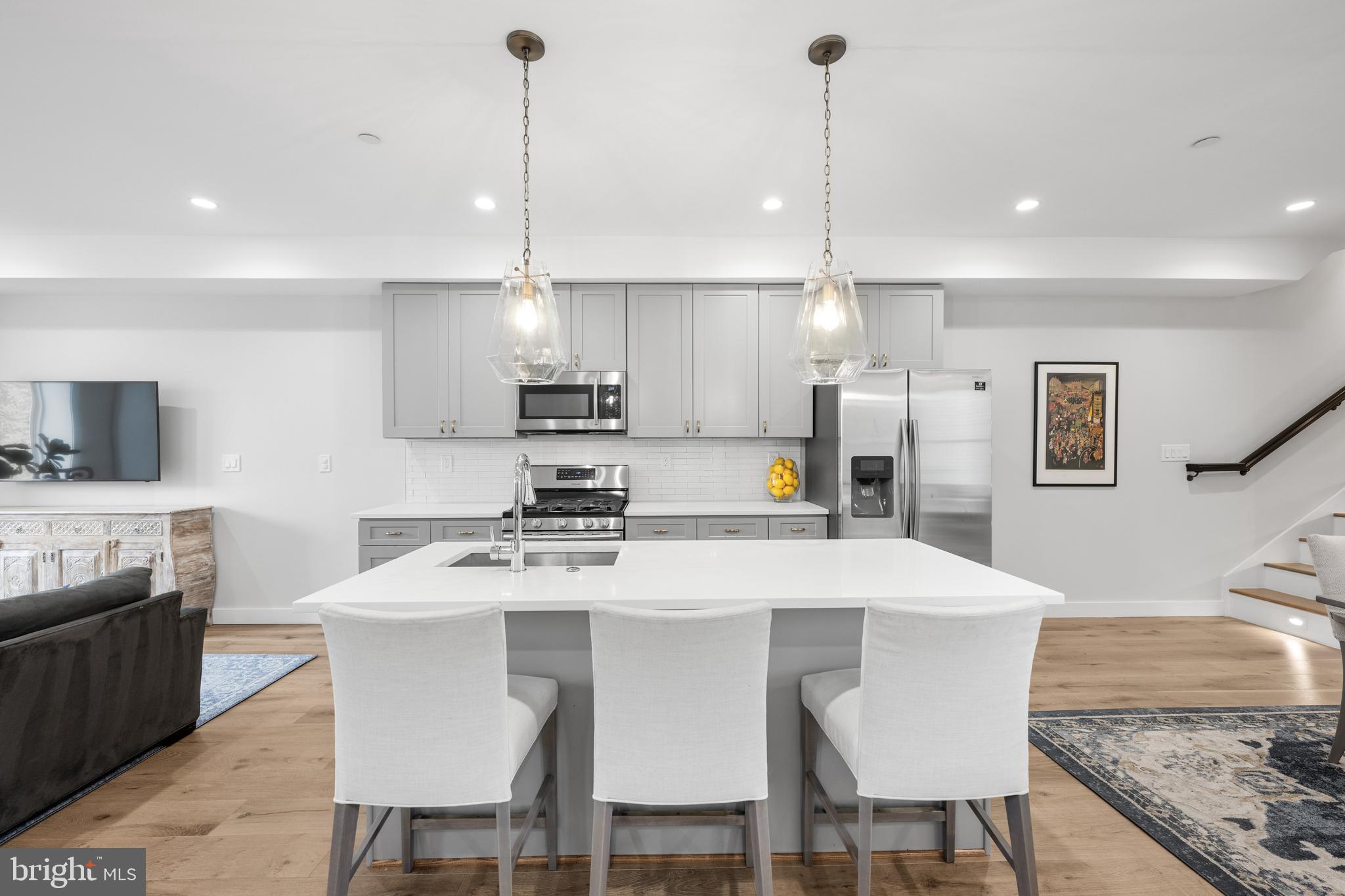127 R Street Northeast, Unit 2 Washington, DC 20002 - Photo 6 of 31 a kitchen with stainless steel appliances kitchen island granite countertop a sink a stove a dining table and chairs
