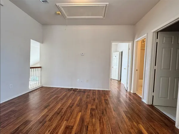 a view of an empty room with wooden floor and window