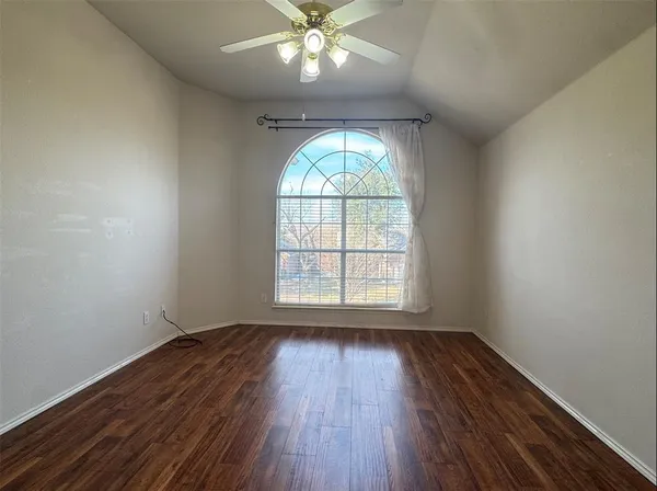 an empty room with wooden floor fan and windows
