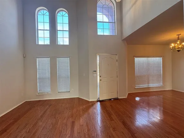 an empty room with wooden floor windows and fireplace