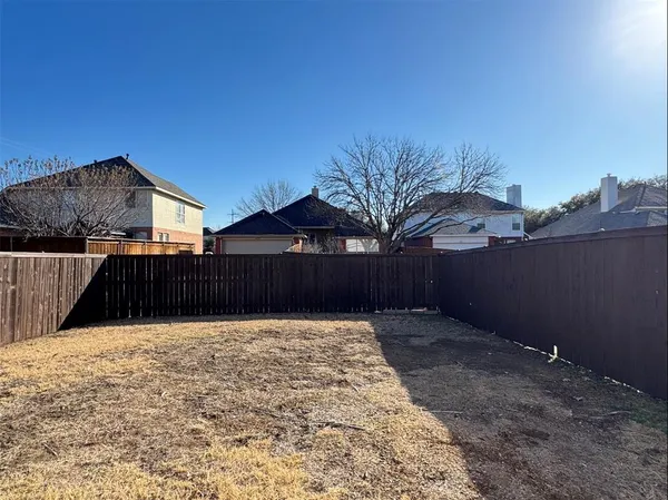 a view of backyard with potted plants and wooden fence