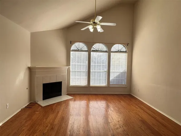 an empty room with wooden floor fireplace and windows