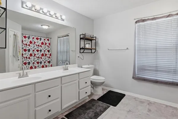 a bathroom with a double vanity sink mirror and toilet