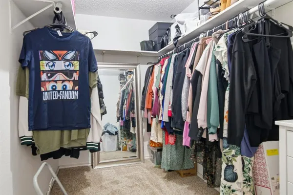 a view of walk in closet with clothes and shoes