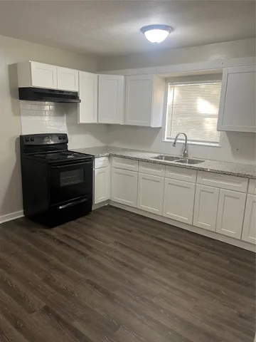 a kitchen with granite countertop a stove a sink and a refrigerator