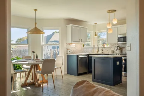 a kitchen with kitchen island granite countertop a sink a stove a dining table and chairs