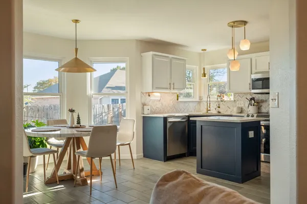 a kitchen with kitchen island granite countertop a sink a stove a dining table and chairs