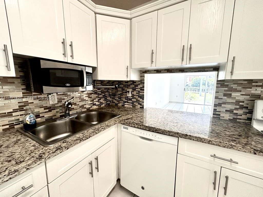 4920 Northwest 79th Avenue, Unit 307 Doral, FL 33166 - Photo 2 of 21 a kitchen with granite countertop a sink and a stove top oven