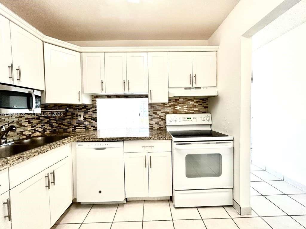 4920 Northwest 79th Avenue, Unit 307 Doral, FL 33166 - Photo 3 of 21 a kitchen with granite countertop white cabinets and white appliances