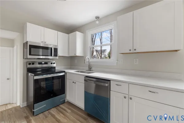 a kitchen with cabinets stainless steel appliances a sink and a window