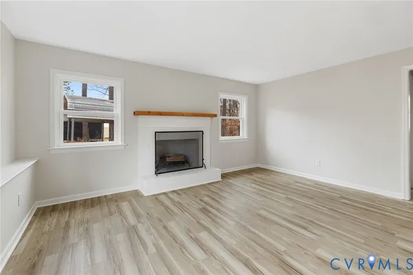 a view of empty room with wooden floor and fireplace