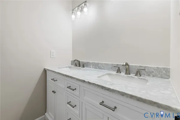a bathroom with a granite countertop sink and white cabinets
