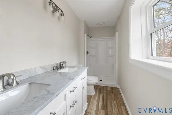 a bathroom with a granite countertop sink a toilet and a window