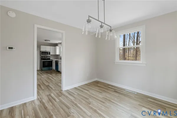 a view of empty room with wooden floor and kitchen view