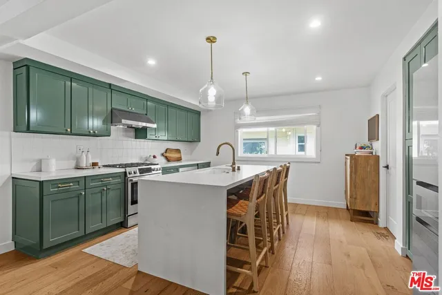 a kitchen with stainless steel appliances granite countertop a sink a stove a refrigerator cabinets and wooden floor