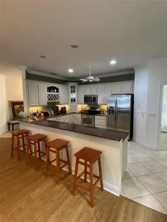 a kitchen with stainless steel appliances granite countertop a table chairs sink and cabinets
