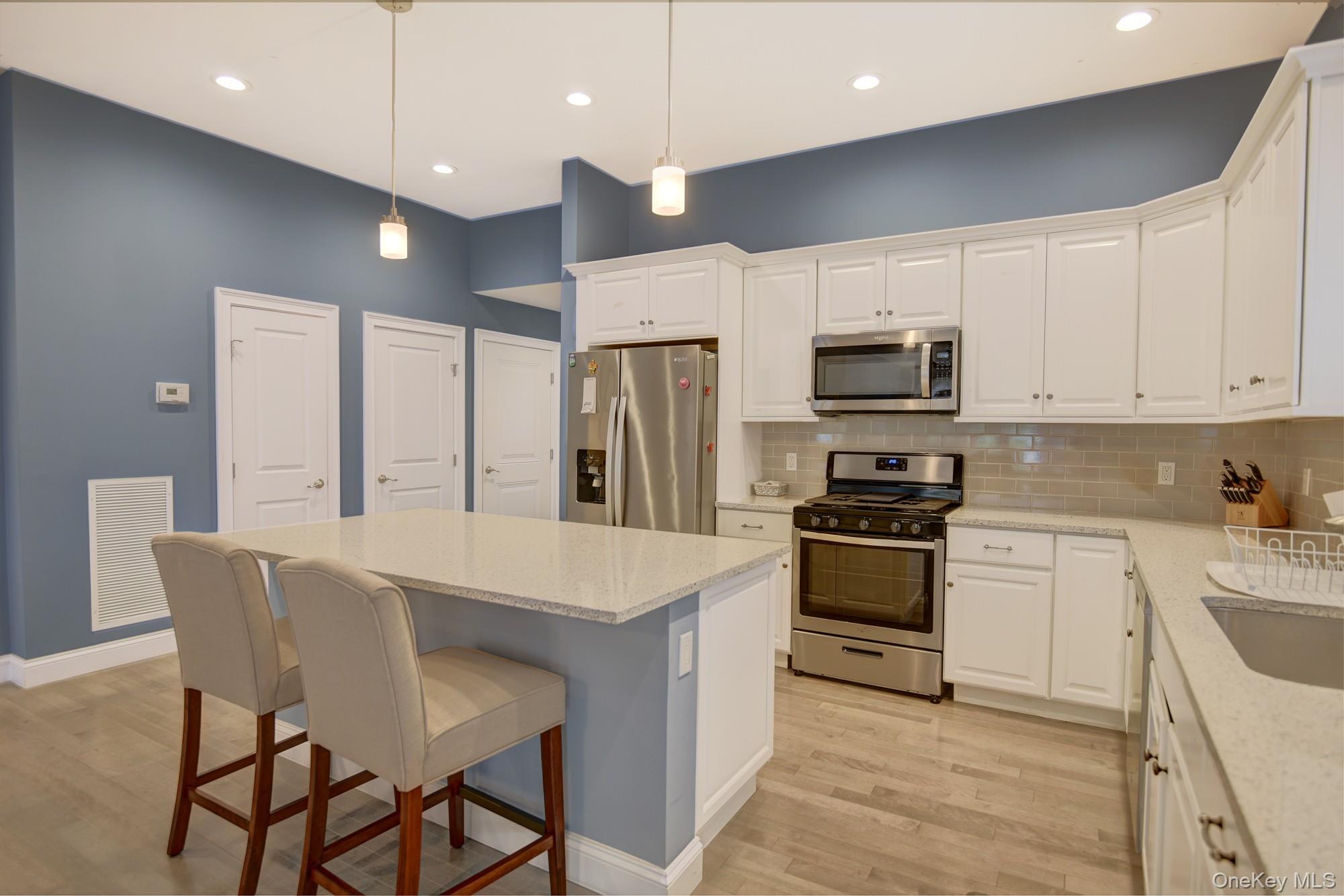 2 Spruce Place Bohemia, NY 11716 - Photo 6 of 34 a kitchen with stainless steel appliances kitchen island granite countertop a stove a sink a refrigerator a microwave oven with a dining table and chairs