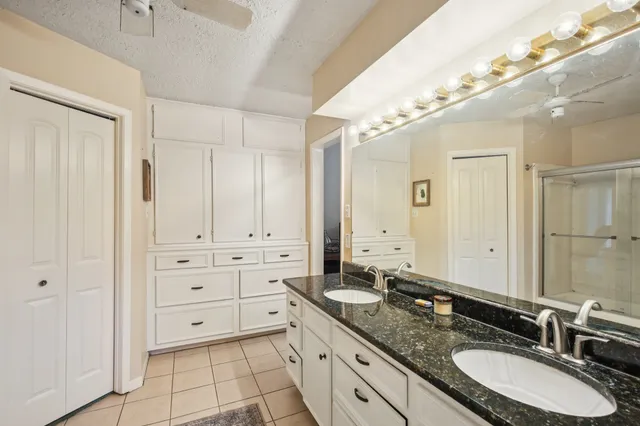 a bathroom with a granite countertop double vanity sink a mirror and a bathtub