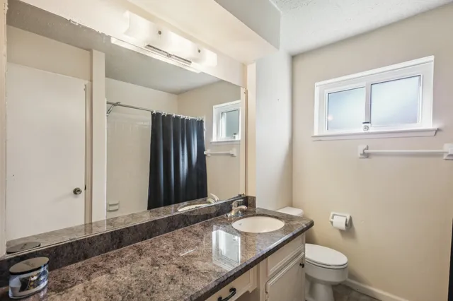 a bathroom with a granite countertop sink and a mirror