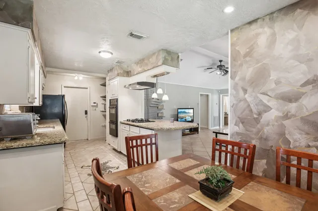a kitchen with stainless steel appliances kitchen island granite countertop a table chairs and a refrigerator