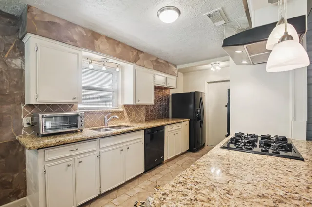 a kitchen with stainless steel appliances a sink a stove a refrigerator and cabinets
