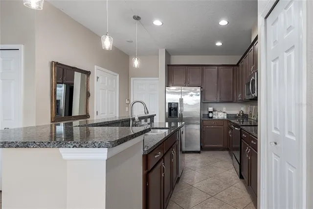 a kitchen with kitchen island granite countertop a sink stove refrigerator and cabinets