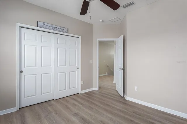 an empty room with wooden floor cabinet and windows