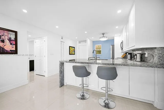 a kitchen with granite countertop a counter space chairs stainless steel appliances and cabinets
