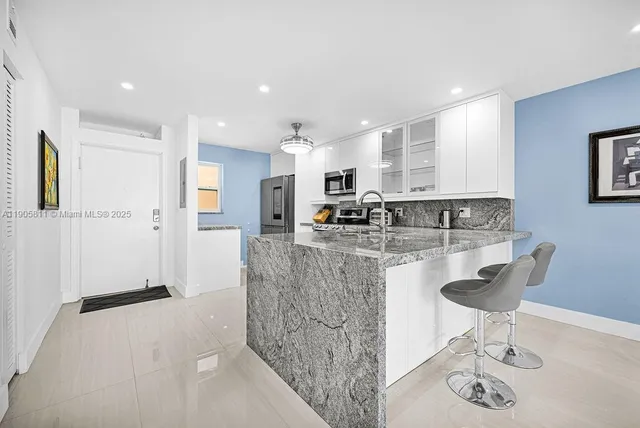 a kitchen with stainless steel appliances kitchen island granite countertop a sink and a refrigerator