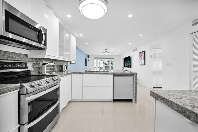 a kitchen with stainless steel appliances granite countertop a stove top oven a sink and a microwave