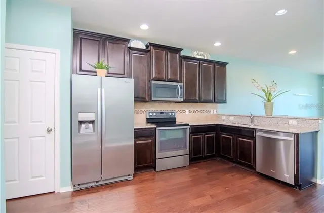 a kitchen with stainless steel appliances granite countertop a refrigerator stove and sink
