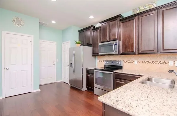 a kitchen with stainless steel appliances granite countertop a refrigerator stove top oven and sink