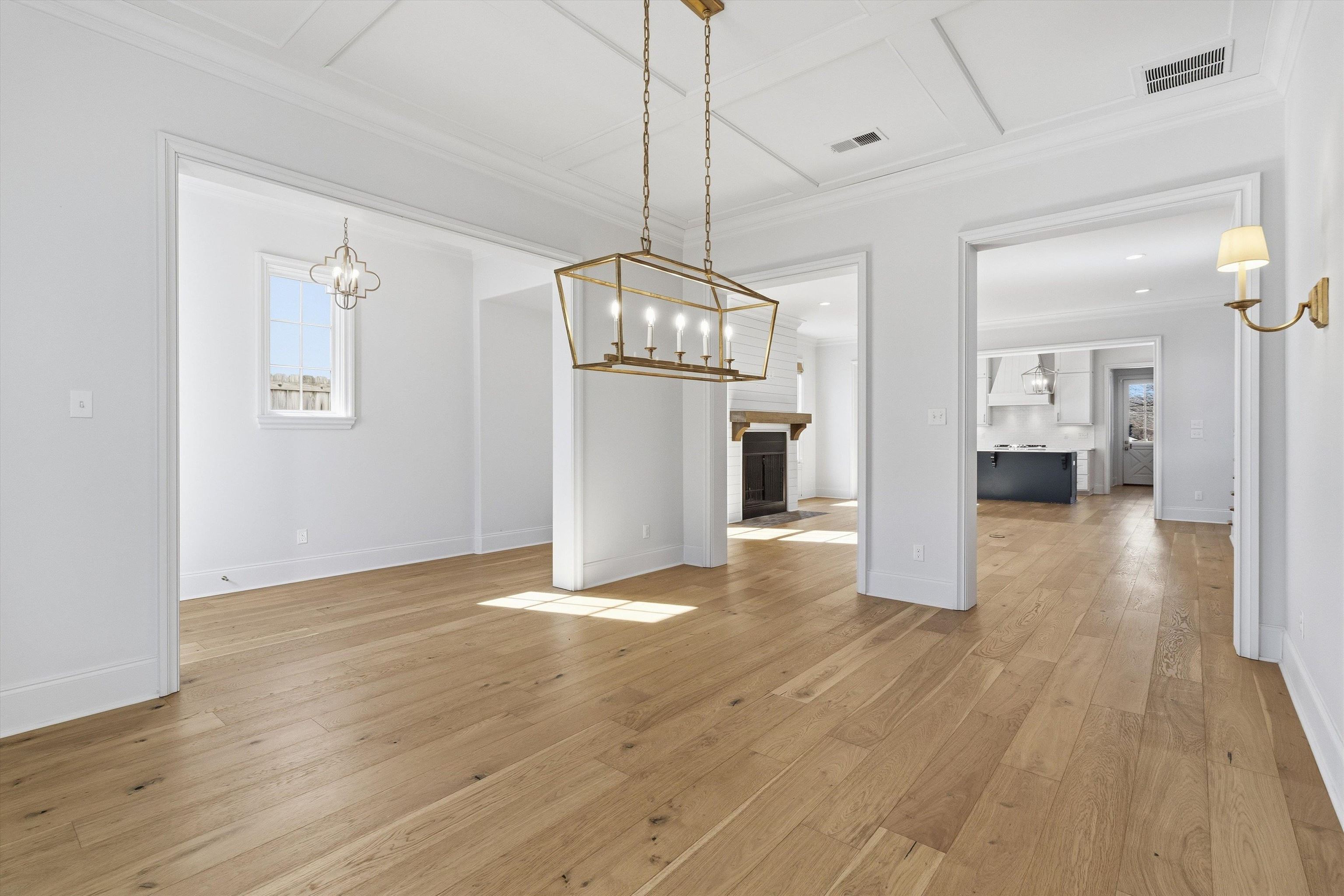 Unfurnished dining area with a fireplace, light wood-style flooring, crown molding, coffered ceiling, and hanging lights