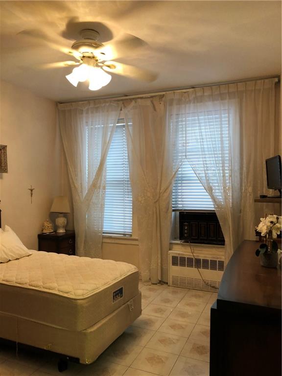 1063 64th Street Brooklyn, NY 11219 - Photo 12 of 20 a bed sitting in a bedroom next to a window