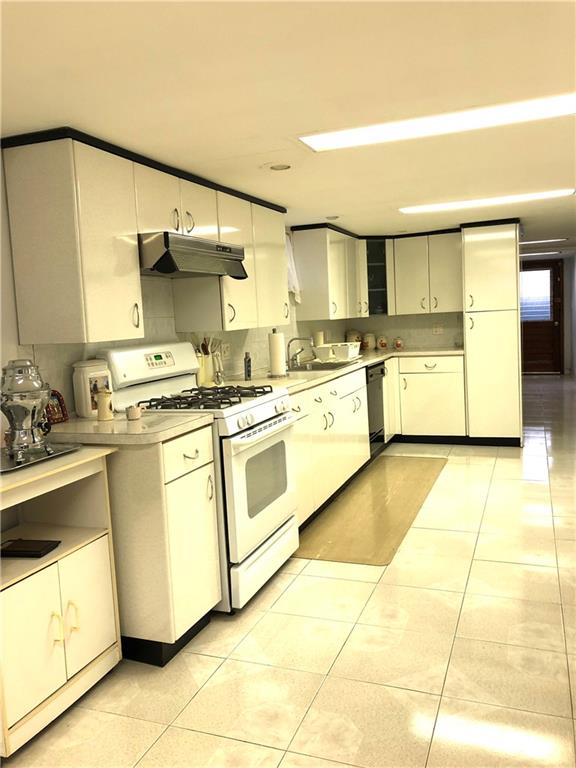 1063 64th Street Brooklyn, NY 11219 - Photo 18 of 20 a kitchen with a stove top oven sink and cabinets