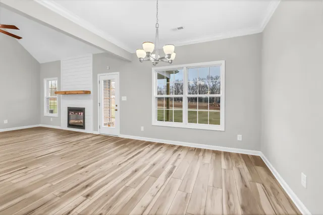 a view of an empty room with wooden floor fireplace and a window