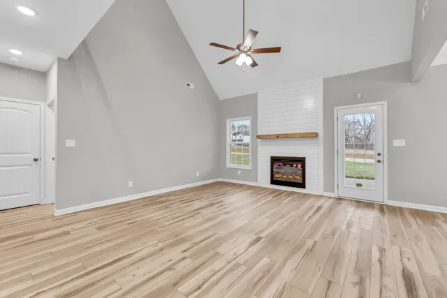 an empty room with wooden floor fireplace and windows
