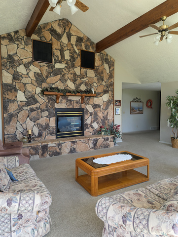 1040 West Mill Road Ferron, UT 84523 - Photo 44 of 117 Vaulted ceiling with exposed wood beams, stone-faced fireplace with hearth, built-in fireplace insert, and ceiling fans