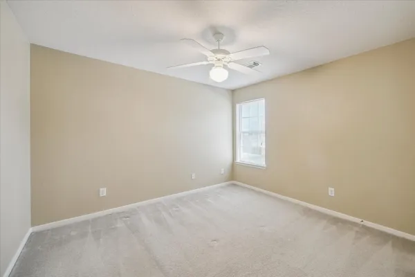 an empty room with a window and a fan