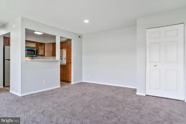 a view of an empty room with kitchen and a window