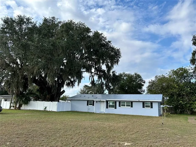 a view of a house with a big yard and large trees