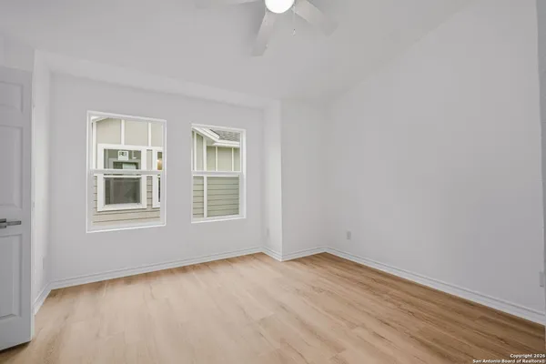 a view of empty room with wooden floor and fan