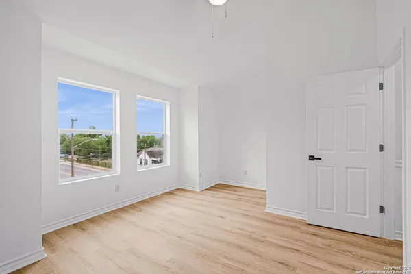a view of an empty room with window and wooden floor