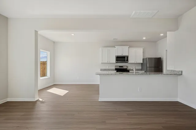 a view of kitchen with microwave stove refrigerator and cabinets