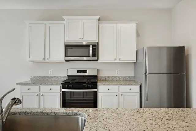 a kitchen with a refrigerator stove and white cabinets