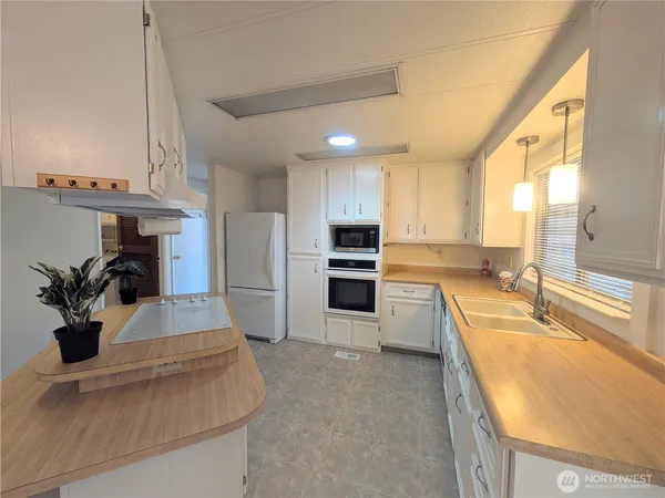 a living room with stainless steel appliances furniture a chandelier and a view of kitchen